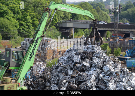 crane driver lifting compacted scrap metal onto pile awaiting transfer to steel works for re-smelting united kingdom Stock Photo