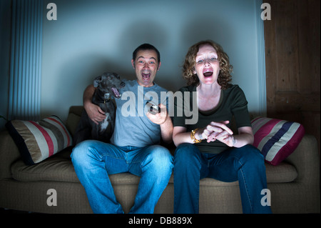 middle aged couple and dog watching the television laughing Stock Photo