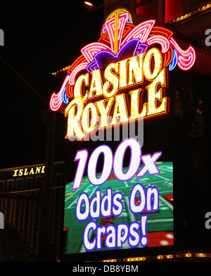 Night view electric billboard green craps table '100X Odds on Craps' below yellow pink neon sign, Casino Royale, Las Vegas Strip Stock Photo