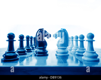 Chess pieces facing off on chessboard as a metaphor for business and war Stock Photo