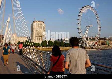 tourists walk across golden jubilee bridges towards southbank London England UK Stock Photo