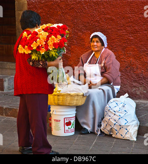 A FLOWER VENDOR stops to speak with a woman selling baked goods - GUANAJUATO, MEXICO Stock Photo