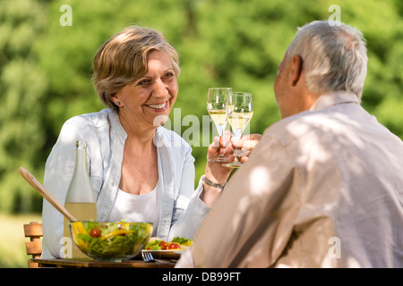 Happy senior citizens clinking glasses in garden Stock Photo