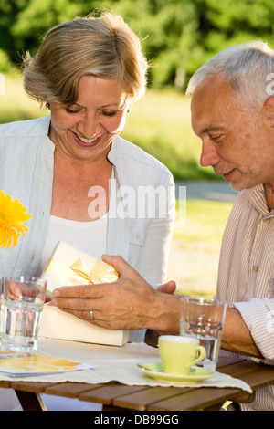 Elderly married couple opening present together Stock Photo