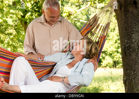 Happy senior couple relax hammock outdoors looking at each other Stock Photo