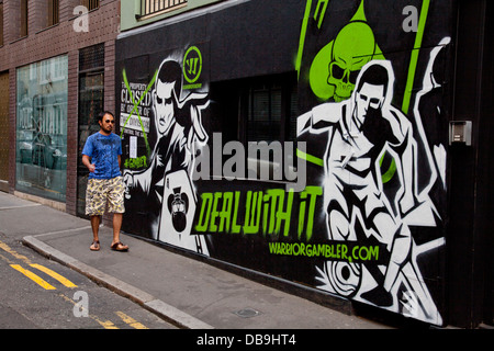 Young man walks past Graffiti art in Shoreditch, London Stock Photo