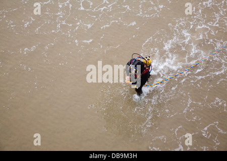 Diver walking into sea in full equipment UK Stock Photo
