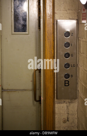 The sliding door and control panel of an old fashioned lift elevator Stock Photo