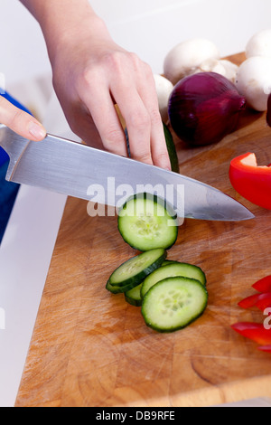 female hands chopping vegetables on a wooden board in the kitchen Stock Photo