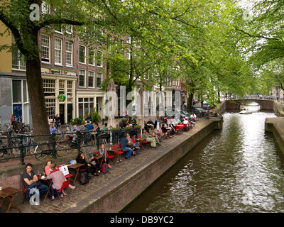 People relaxing along the Leliegracht canal in the city centre of Amsterdam, the Netherlands Stock Photo