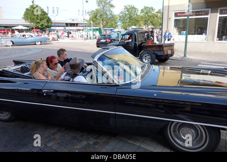 Rockabilly style people riding in a classic car on the road in Varberg town, Sweden Stock Photo