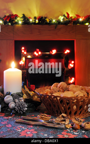 Basket of walnuts and hazelnuts with a candle and fireplace to the rear, England, UK, Western Europe. Stock Photo
