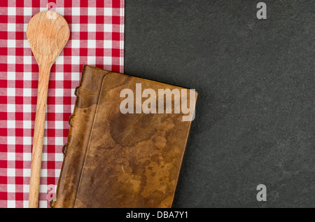 Wooden spoon and coockbook on a slate plate Stock Photo