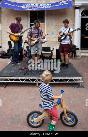A boy on his bicycle watches local band Lemon Soul perform in Lewes town centre during The GOTR Festival, Lewes, Sussex, England Stock Photo