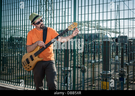 Young musician playing bass guitar in the street Stock Photo