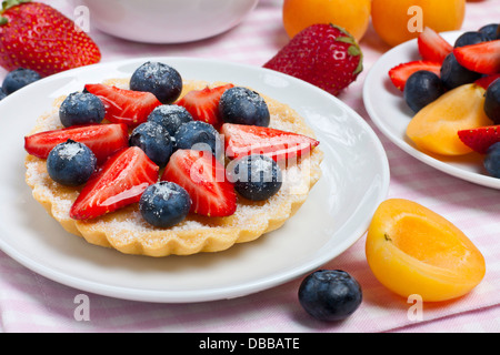 Small tart garnished with fresh berries on a white plate Stock Photo