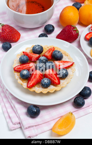 Small berry tart on a plate with a cup of tea Stock Photo