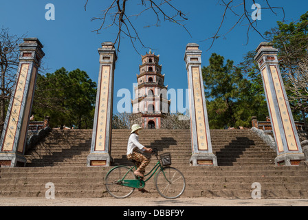 An unidentified woman rides her bicycle in front of the Thien Mu Pagoda on January 12, 2008 in Hue, Vietnam. Stock Photo