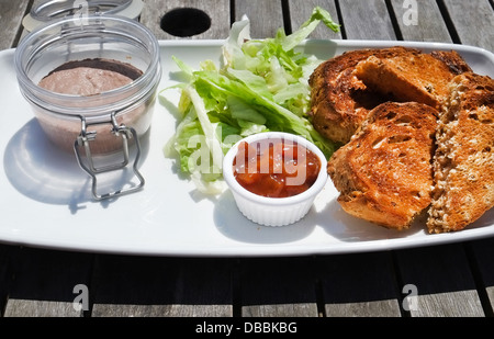 Pot of chicken liver pate with lettuce, chutney and toasted granary bread - served as a pub lunch in UK Stock Photo