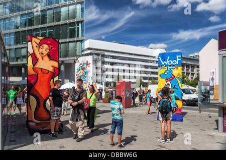 People, buildings and colourful pieces of the Berlin wall at Checkpoint Charlie Border post, Friederichstrasse, Berlin Stock Photo