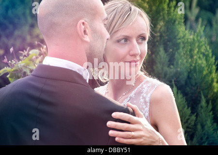 Bride and groom posing in the garden in the afternoon sun Stock Photo