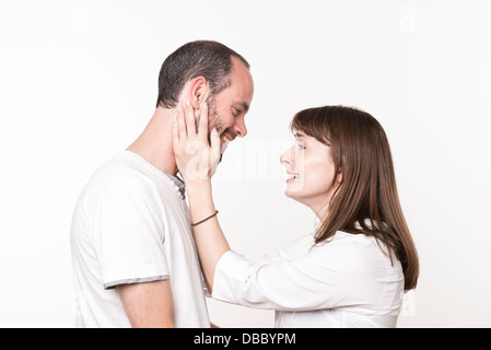 Loving adult couple looking at each other, woman holding man's face between her hands Stock Photo