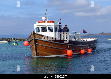 One of the boats that  make the trip to Staffa from the Isle of Mull Scotland  preparing to dock  at the jetty in Fionnphort. Stock Photo