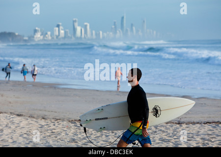 Surfer on beach at Burleigh Heads with Surfers Paradise skyline in background. Burley Heads, Gold Coast, Queensland, Australia Stock Photo