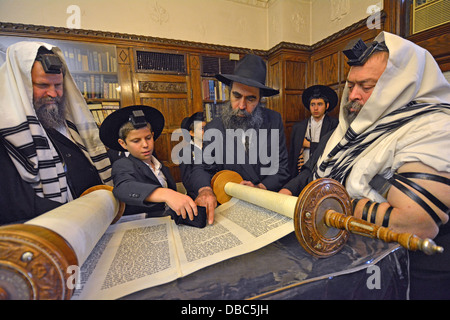 Religious Jews pray in the Rebbe's study at Lubavitch Headquarters in Brooklyn, New York. Bar Mitzvah boy blesses the Torah. Stock Photo