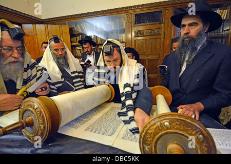 Religious Jews pray in the Rebbe's study at Lubavitch Headquarters in Brooklyn, New York. A man blesses the Torah. Stock Photo