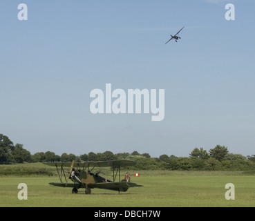 Polikarpov Po2 taxing on grass runway with Westland Lysander flying in the background Stock Photo