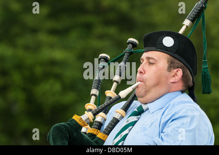 A Scottish piper ignores the rain to play a haunting lament on his bagpipes. Stock Photo