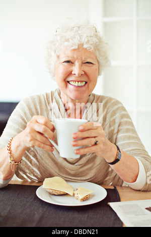 Smiling old lady having her breakfast at home Stock Photo