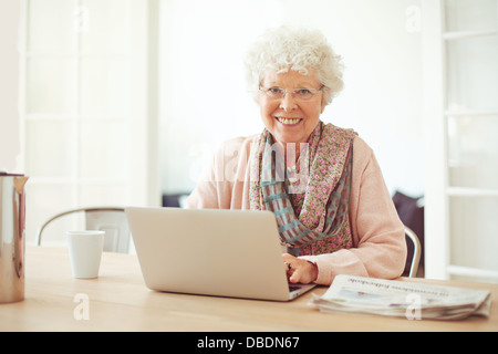 Cheerful senior woman using laptop as recreation at home Stock Photo