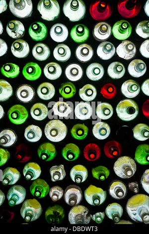 Wall of a building or home constructed with thousands of very old different colored bottles. Stock Photo