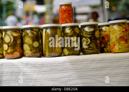 Jars of Pickled Cucumbers and Corn Relish, Displayed on a Table, at an Outdoor Farmer's Market Stock Photo