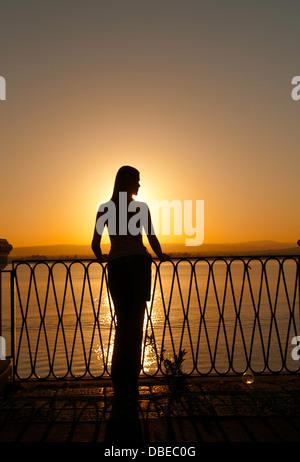 A young woman looks at the sunset in Siracusa. Italy Stock Photo