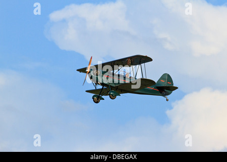 Biplane in flight against a blue sky with cumulus clouds. Stock Photo