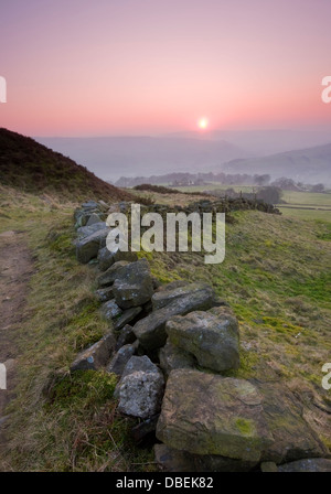 A typical Yorkshire dry stone wall leading the eye down towards a misty valley Stock Photo