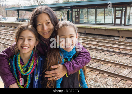 Mother and daughters smiling at train station Stock Photo
