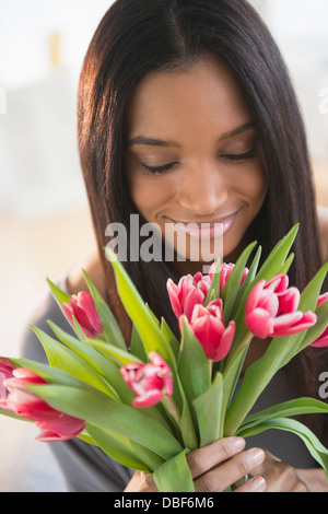 Mixed race woman smelling flowers Stock Photo