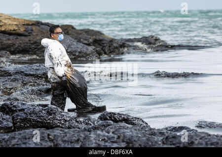 Koh Samet, Rayong, Thailand. 30th July, 2013. An oil spill cleanup worker stands in the surf on Ao Prao beach on Koh Samet island. About 50,000 liters of crude oil poured out of a pipeline in the Gulf of Thailand over the weekend authorities said. The oil made landfall on the white sand beaches of Ao Prao, on Koh Samet, a popular tourists destination in Rayong province about 2.5 hours southeast of Bangkok.  © ZUMA Press, Inc. © ZUMA Press, Inc. Credit:  ZUMA Press, Inc./Alamy Live News Stock Photo