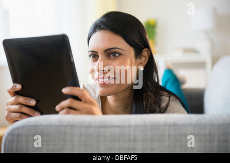 Indian woman using tablet computer on sofa Stock Photo
