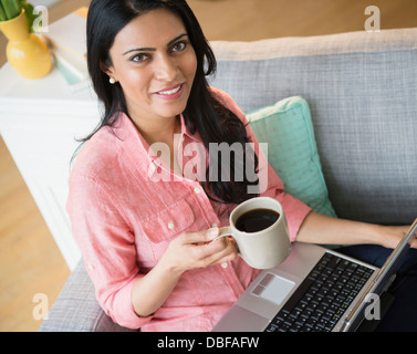 Indian woman using laptop on sofa Stock Photo