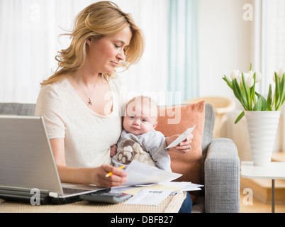 Caucasian mother with baby paying bills Stock Photo