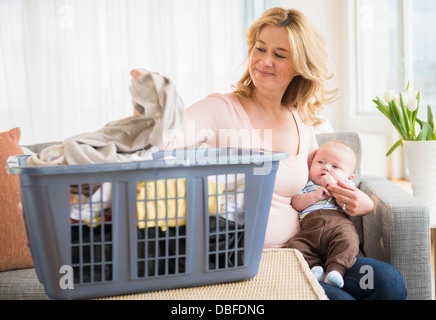 Caucasian mother with baby sorting laundry Stock Photo