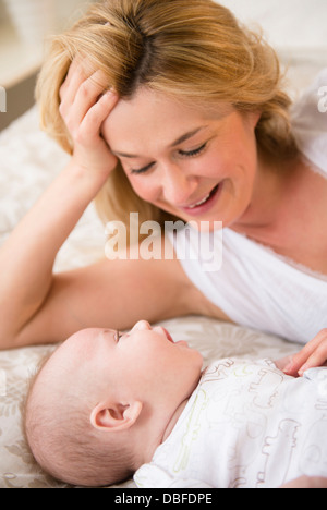 Caucasian mother and baby laying on bed Stock Photo