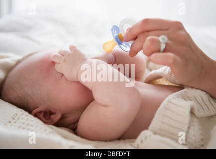 Caucasian mother giving baby pacifier Stock Photo