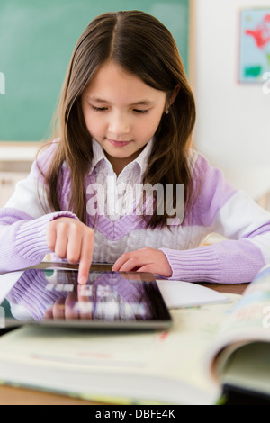 Mixed race girl using tablet computer in class Stock Photo