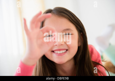 Mixed race girl making O.K. sign with fingers Stock Photo